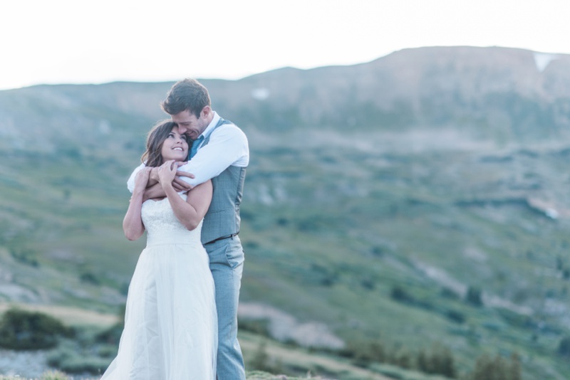 Loving couple smiles and kisses mountain wedding 