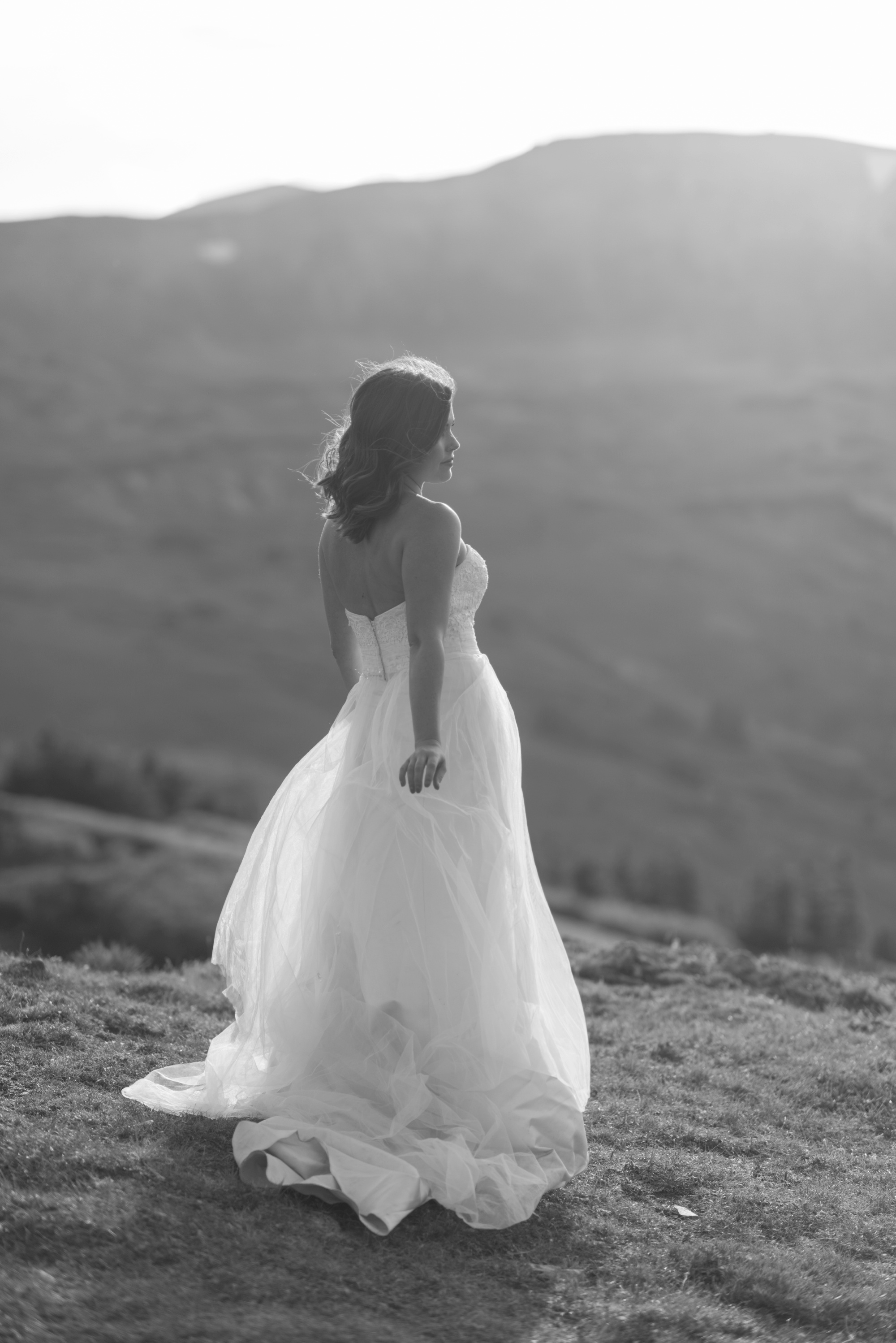 Newly wed bride stands in the evening sunlight among the mountain vista on top of Loveland Pass 