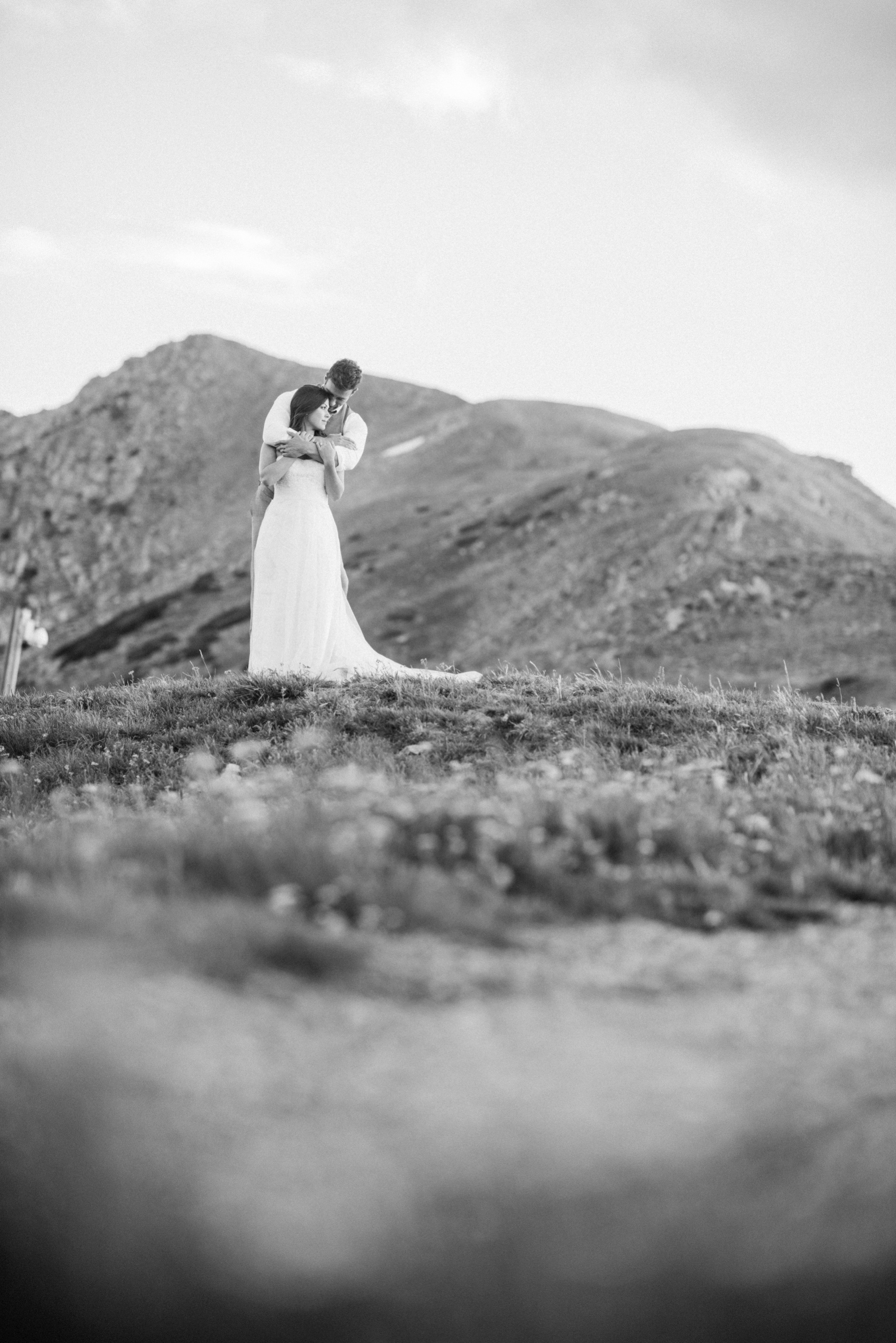 Black and white capture of stunning newly wed couple on top of mountain during intimate wedding