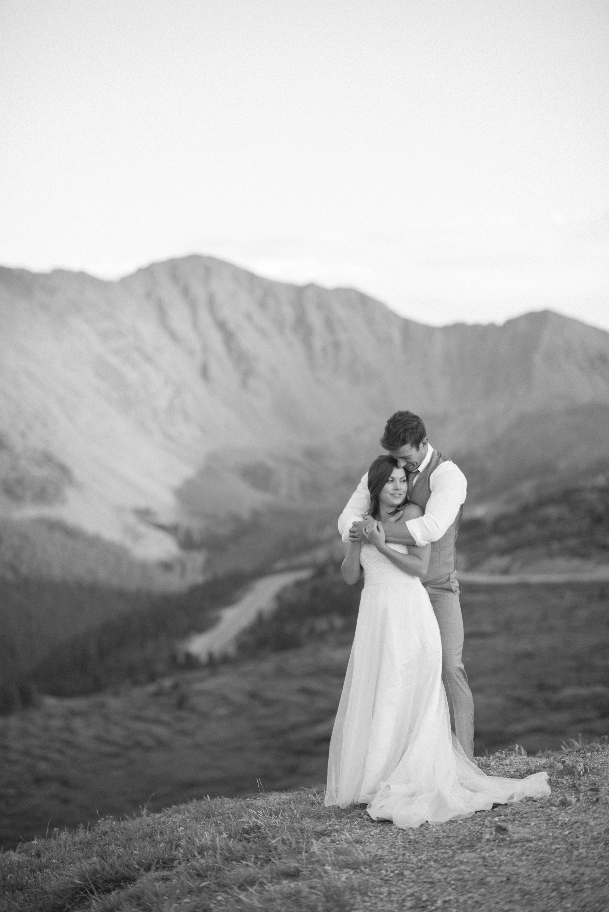 Holding one another close surrounded by mountain vistas during their mountain elopement