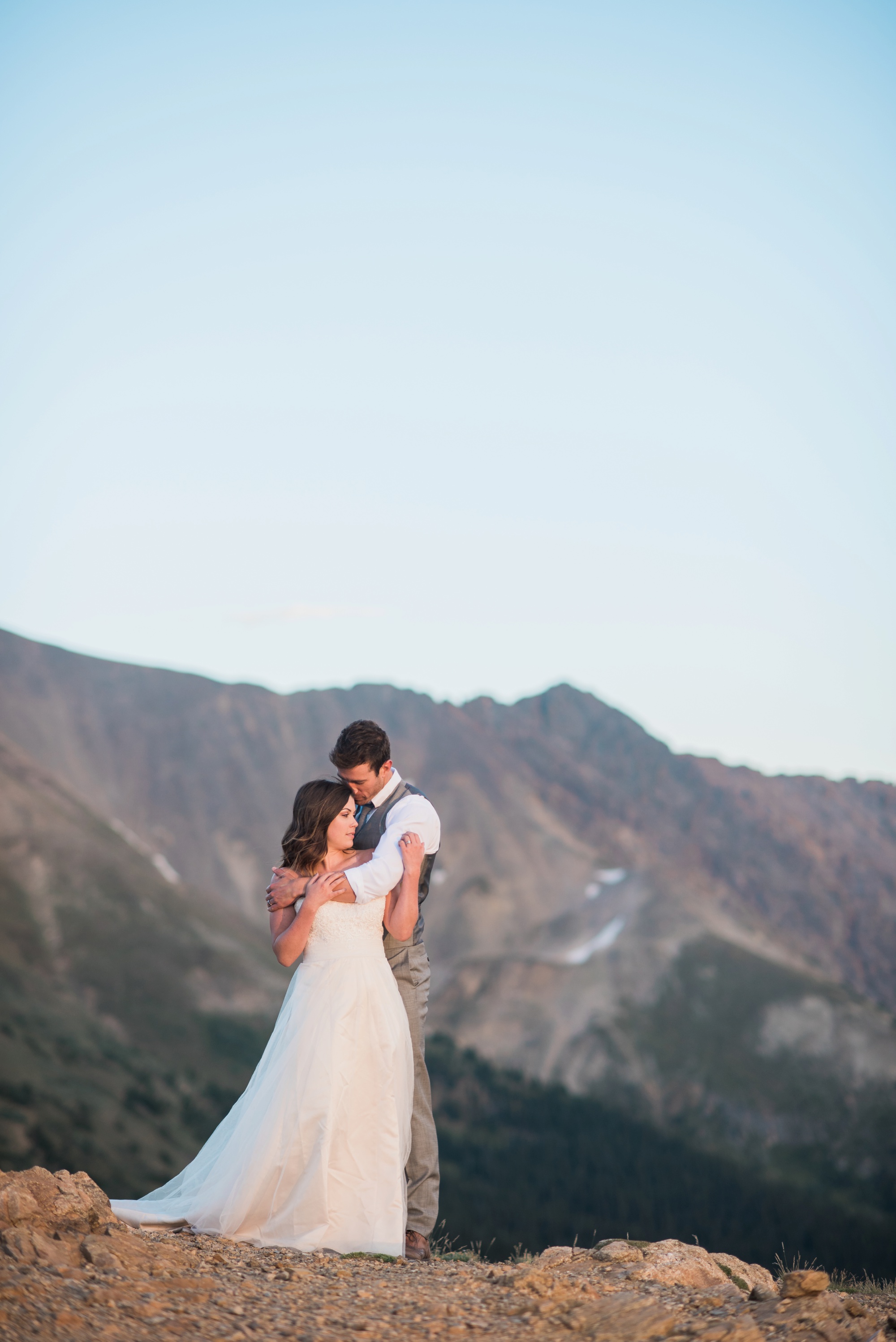 Bathed in warm sunlight a newly wed couple snuggle close on top of Loveland Pass 