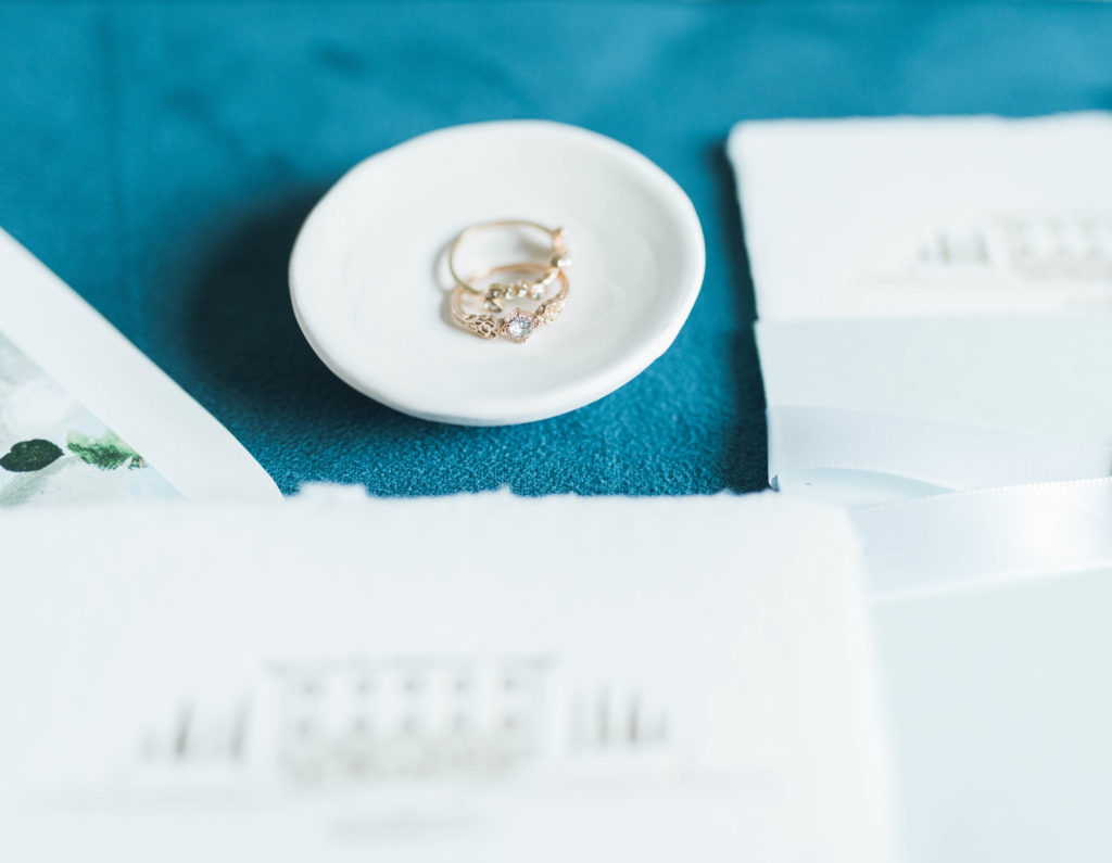 vintage Italian engagement rings photographed on teal with wedding invitation suite