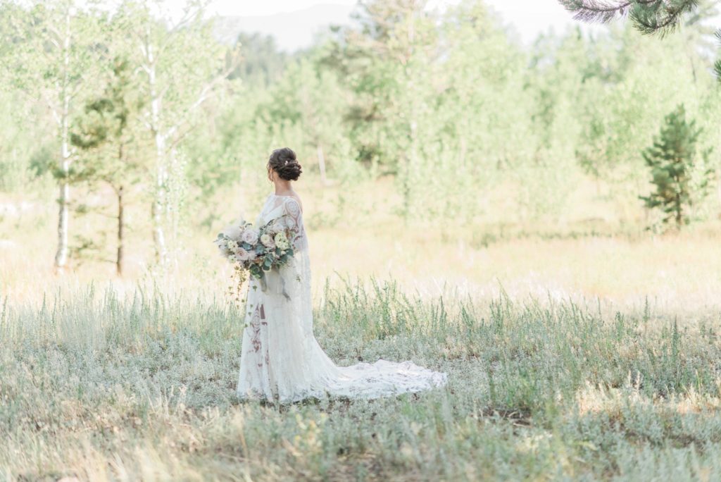 Bride with bouquet in field near Aspen grove in Colorado